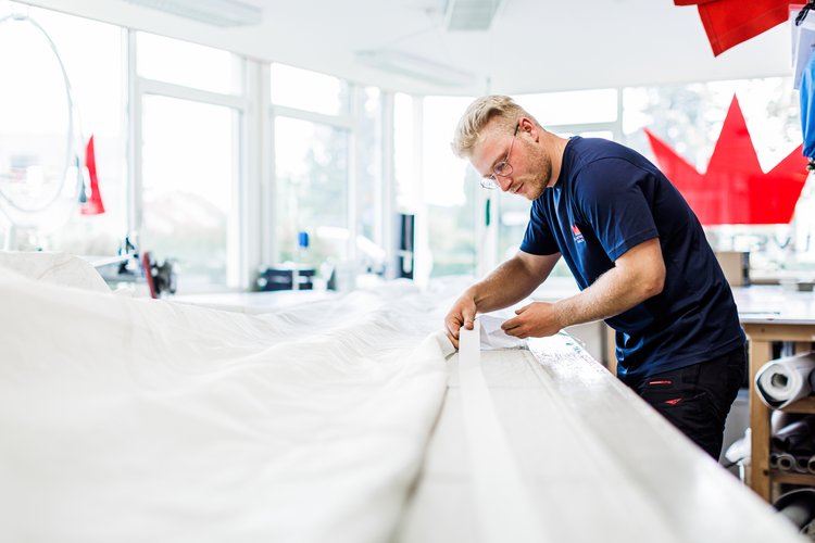 Ein Mann arbeitet in einer Segelmacherei an einem Segel